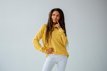 Portrait black young woman posing in yellow sweater in bright spacious studio  