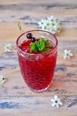 a red cocktail is an alcoholic drink, covered with a fresh bright green mint leaf and currant berries.