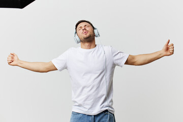 Cheerful tanned handsome man in basic t-shirt headphones listen favorite song dance smile posing isolated on over white studio background. Copy space Banner Mockup. Music Cool playlist concept