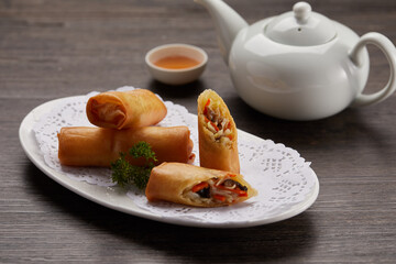 Crispy Vegetable Spring Roll with sauce served in a dish side view on dark background