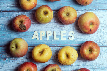 Yellow and red tasty raw apples fruit with apples wooden word written on a blue board