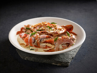 Signature Creamy Butter Sri Lankan Crab topped with Coconut Crumbs served in a dish side view on dark background