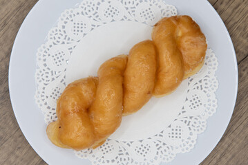 Overhead view of tempting fresh from the oven glazed twist donut from the bakery served on a plate