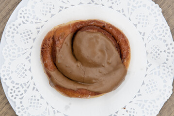 Overhead view of tempting fresh from the oven cinnamon roll maple donut from the bakery served on a plate