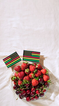 Juneteenth Day Picnic Background With Black Liberation African American Flags, Sweet Salad With Cherries And Strawberries, Strawberry Cheesecake