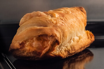 Baked bun with ham, cheese on tray in electric oven - close up view. Homemade bakery, food, cooking and pastry concept