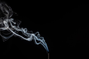 incense stick with smoke against black background