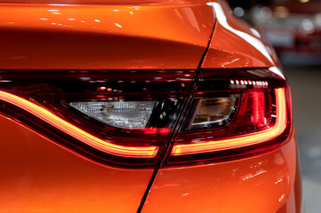 Tail light of nice and new orange sport suv car in modern garage.