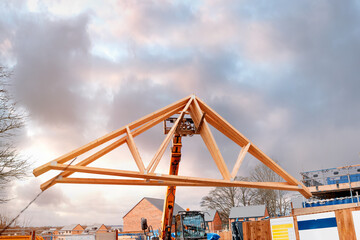 Heavy machinery shifting roof trusses on new residential housing development construction site