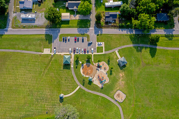 An overhead view of a community park with a water park, grassy fields, a pavilion, a gazebo, a...