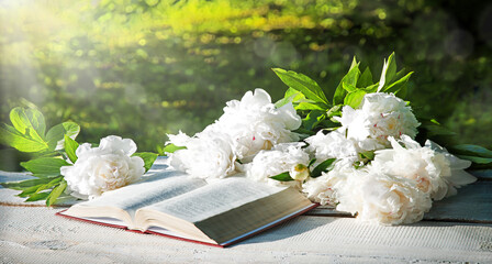 Bible and a bouquet of peonies on a table in the garden