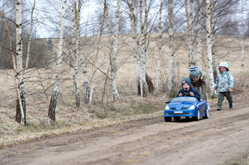 Fototapeta na wymiar Three happy kids having fun drive a blue toy car, road trip adventure concept