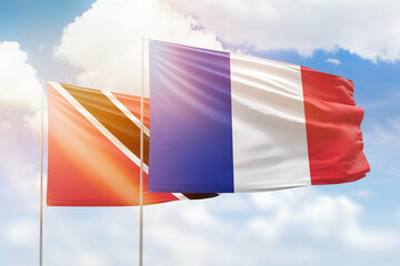 Sunny blue sky and flags of france and trinidad and tobago