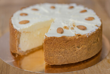 Vanilla cheesecake on the plate. Sweet creamy cake with almond nut. Yogurt dessert. Cheesecake in cafe showcase. Fresh pastry in cakestand. Round cut cake. Delicious bakery.