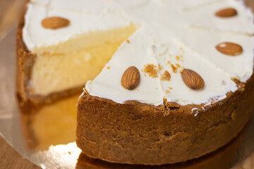 Vanilla cheesecake on the plate. Sweet creamy cake with almond nut. Yogurt dessert. Cheesecake in cafe showcase. Fresh pastry in cakestand. Round cut cake. Delicious bakery.