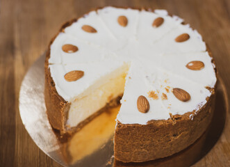 Vanilla cheesecake on the plate. Sweet creamy cake with almond nut. Yogurt dessert. Cheesecake in cafe showcase. Fresh pastry in cakestand. Round cut cake. Delicious bakery.