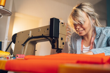 Tailor woman sitting and sewing on a sewing machine a in studio