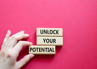 Unlock your Potential symbol. Wooden blocks with words Unlock your Potential. Beautiful red background. Businessman hand. Business and Unlock your Potential concept. Copy space.