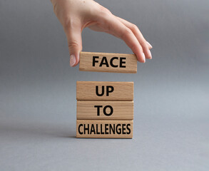 Face up to challenges symbol. Wooden blocks with words Face up to challenges. Beautiful grey background. Businessman hand. Business and Face up to challenges concept. Copy space.