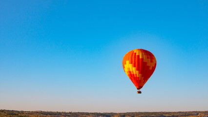 Red and yellow colored hot air balloon on the sky of Cappadocia