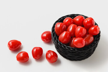 Cherry tomatoes in black basket on white background.