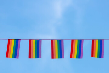 Celebration of pride month, Waving small colourful flags hanging on the rope with blue sky, The...