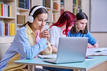 Group of teenage students study in school library
