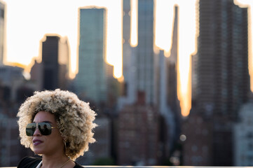 African American Woman with Blonde Afro Standing In Front of the New York Skyline