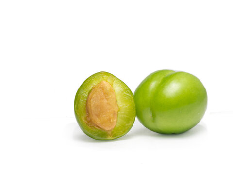 Green Cherry Plum On A White Background. Fruit For Making Tkemali Sauce. Diet Food.   Sweet And Sour Fruit. Juicy Cut Green Plum