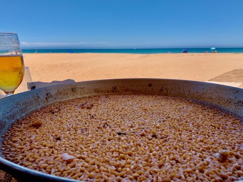 Arroz a banda, a typical valencian meal made with rice and seafood, similar to paella. The beach and the Mediterranean sea are on the background.