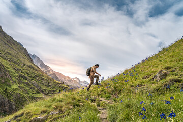 Happy male hiker trekking climbing a mountain. Effort and achievement concept.