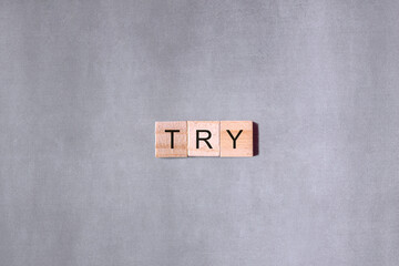 The word "Try" written in tile letters isolated on a grey background.