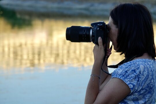 50 year old woman with short hair taking pictures in a lake at sunset