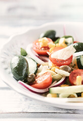 Simple Salad with Green Olives, Cucumber, Cherry Tomatoes and Capers. Bright wooden background. Close up.