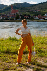 Young girl model on the river bank at the summer weather