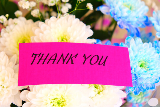 A bouquet of brightly coloured flowers with a cards saying thank you.