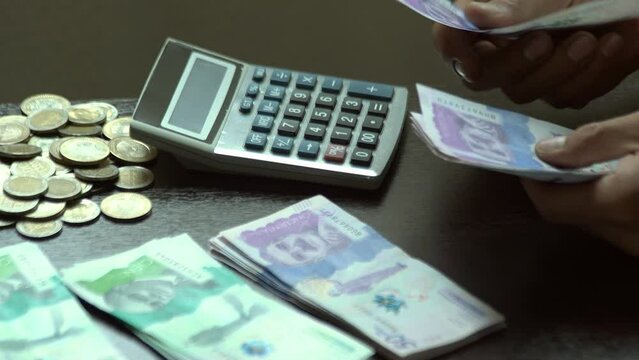 alistando el dinero para las compras del mes esta un joven latino en una mesa de su casa