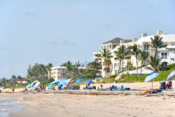Fototapeta na wymiar Tourists and locals with umbrellas on the beach with condos in the background at Lantana Beach in South Florida