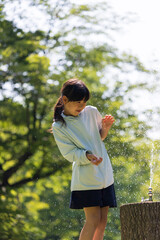 夏の公園で水遊びしている可愛い小学生の女の子の姿