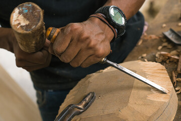 Wood craftsman creating pieces and polishing wooden parts. Latin American worker in his workshop using different tools.  Local carpentry of the town and its operator doing some work.