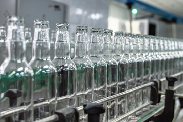 Production line transports empty glass bottles for alcohol