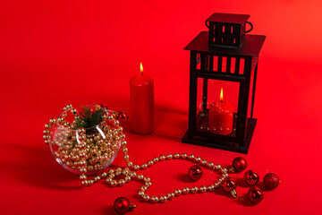 New Year's still life: two red candles and a black lantern, a vase with Christmas decorations on a red background with a place for text