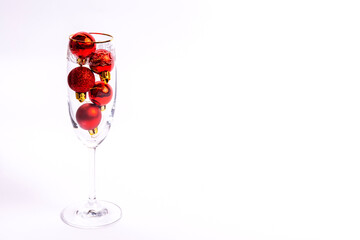 New Year's still life: a glass with red Christmas tree toys on a white background with a place for text