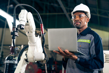 African American factory worker working with adept robotic arm in a workshop . Industry robot...