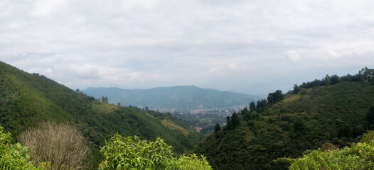 Fototapeta na wymiar Far Away Cityscape of La Estrella Surrounded by Green Mountains