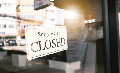 Sign text hangs on the entrance door of the shop, restaurant, cafe. That reads "Sorry, we're closed". Closed due to financial difficulties and economic crisis.