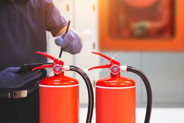 Obraz premium Fire extinguisher has hand engineer inspection checking pressure gauges to prepare fire equipment for protection and prevent emergency and safety rescue and alarm system training concept.