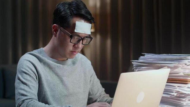 Close Up Of Sick Asian Man Typing Laptop Computer While Working Hard With Documents At Home
