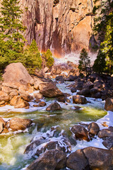 Naklejka premium Rainbow over frosty aqua river in early spring at Yosemite