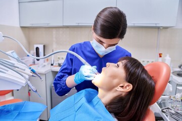 Woman patient treating teeth in clinic, treatment process